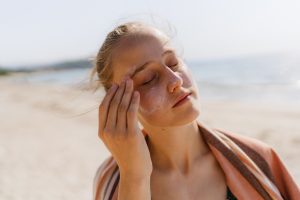 femme sur la plage mettant de la crème solaire