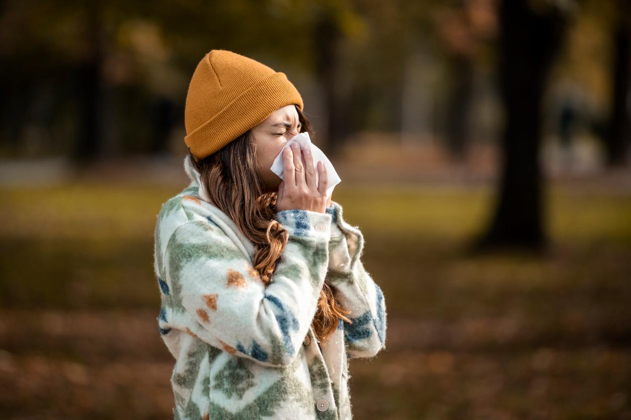 Femme se mouchant avec un bonnet et un pull